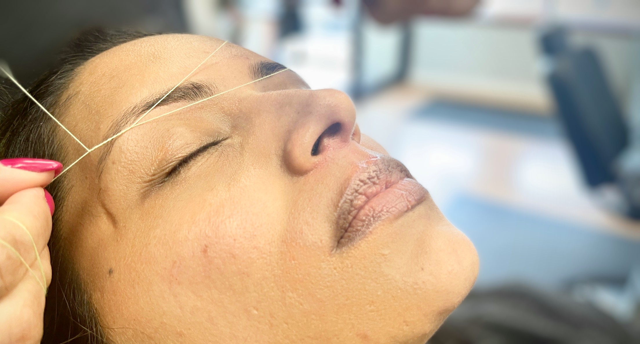 A woman getting her eyebrow threaded